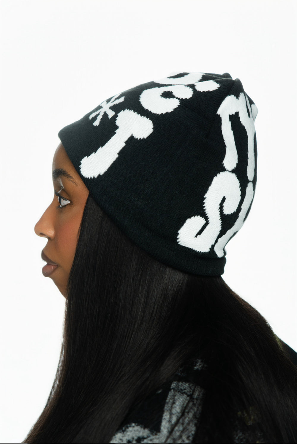 Profile of a woman wearing a black beanie with white text, long dark hair visible.