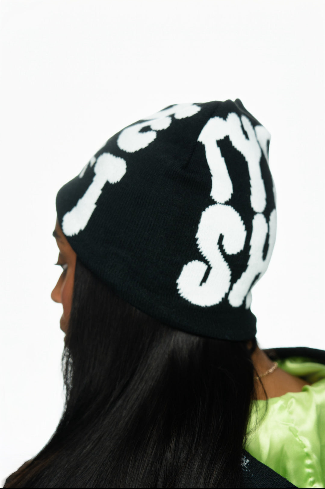 Black beanie with large white text worn by a person with long black hair, against a white background.