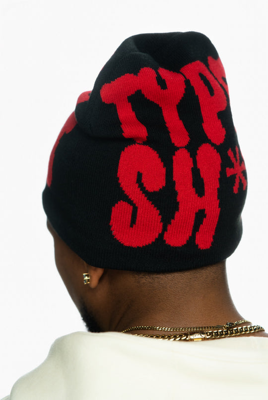 Black beanie with bold red lettering on the back, worn by a person with short hair.
