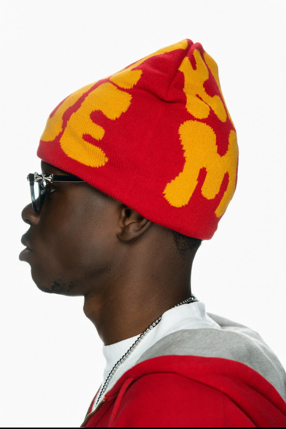 Profile view of a person wearing a red beanie with yellow lettering and glasses.