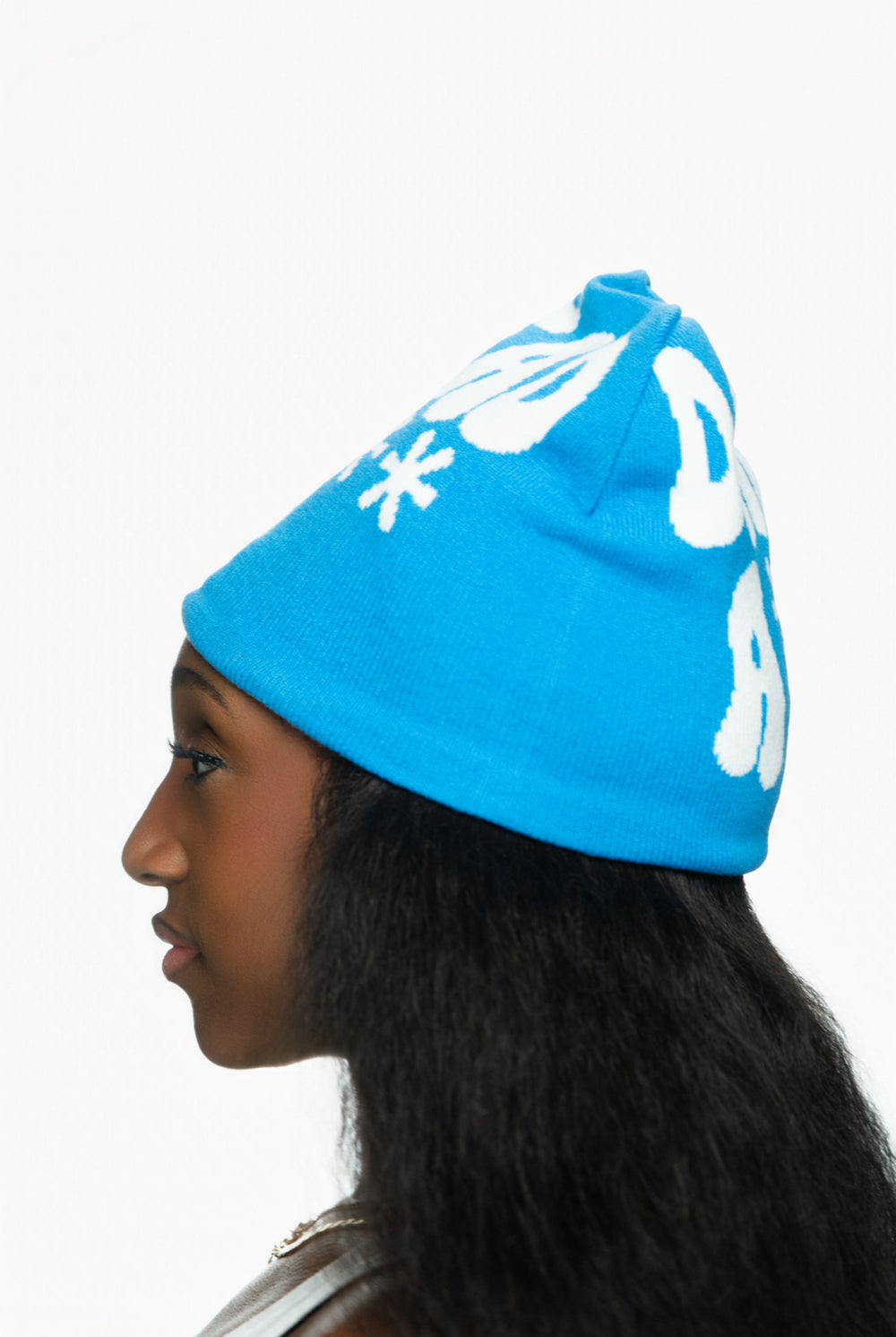 Profile of a person wearing a bright blue beanie with white lettering and textured hair.