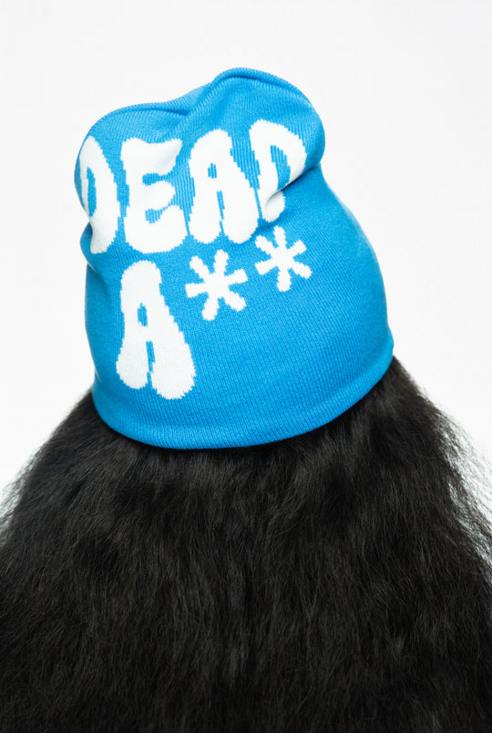 Blue beanie with white text stating "DEAD A**," paired with long, textured black hair.