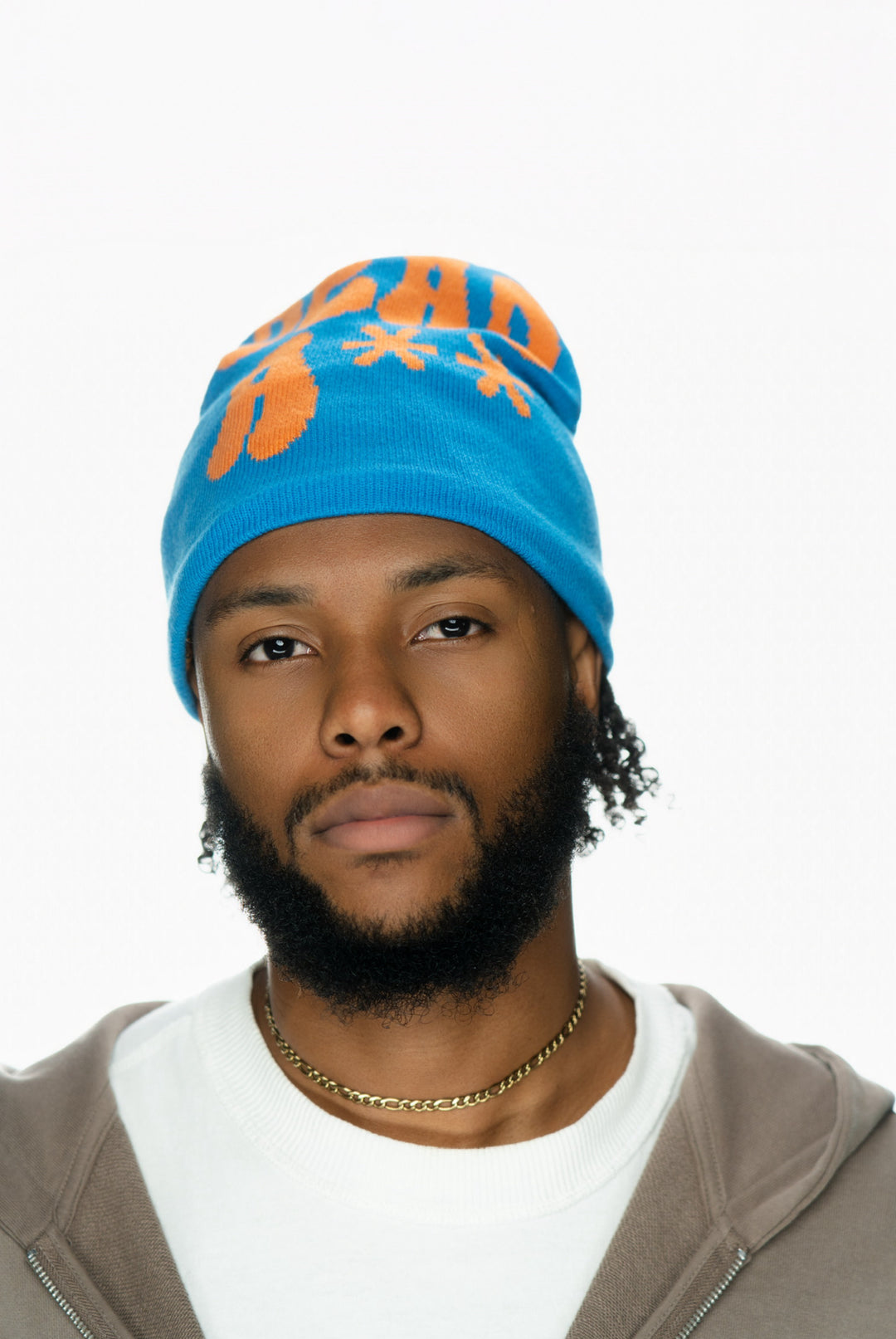 Man with a beard wearing a blue beanie and a brown hoodie, looking directly at the camera.