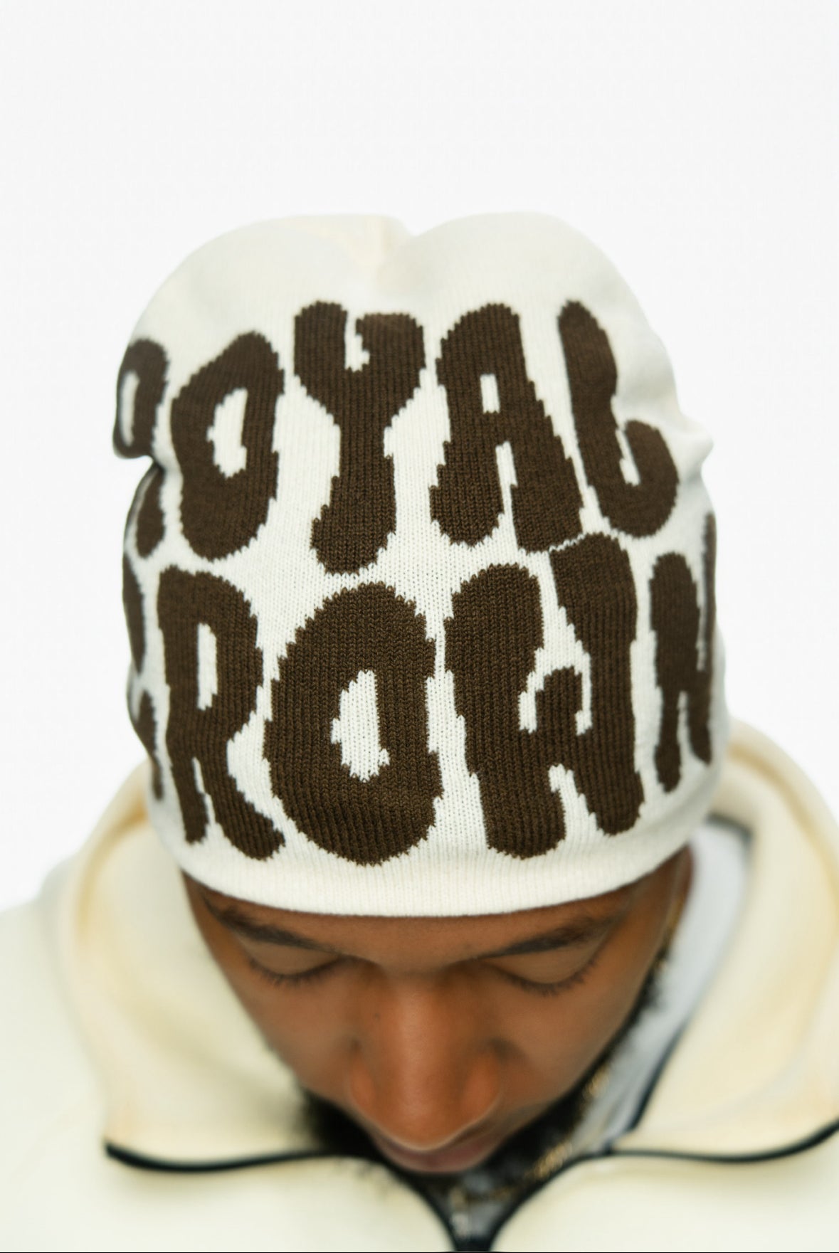 Beanie with "ROYAL CROWN" in bold brown letters worn by a person, viewed from above.