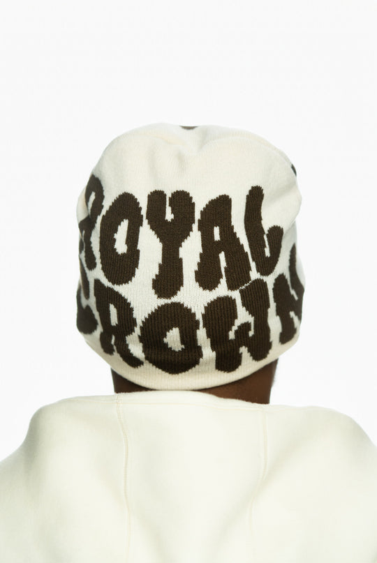 Cream beanie with bold brown lettering reading "ROYAL CROWN," worn by a person from behind.